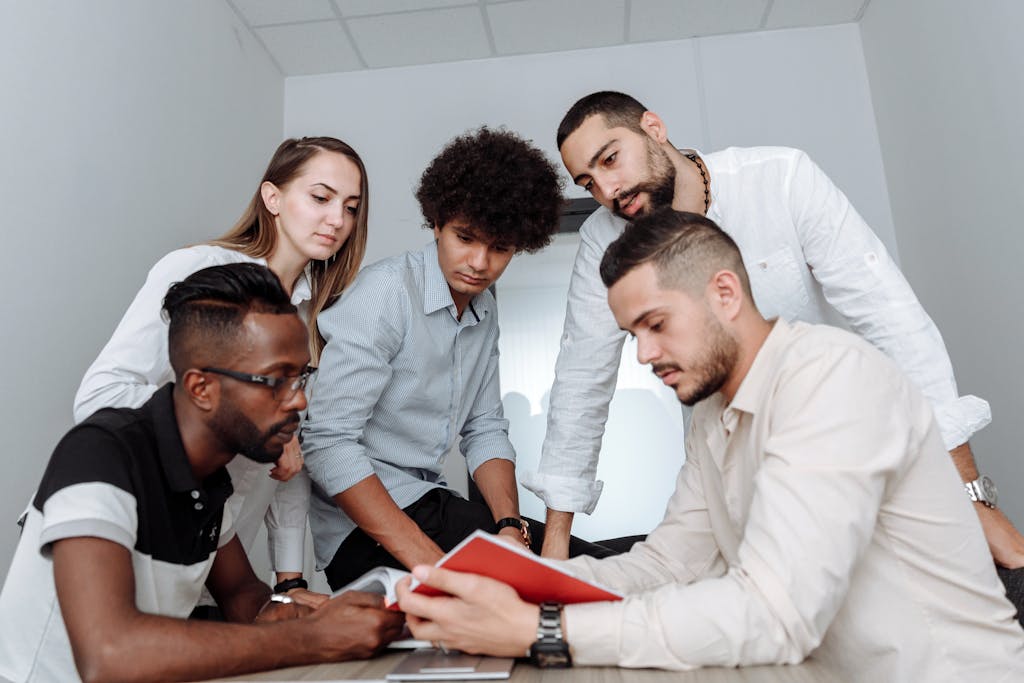 How Understanding Maslow’s Hierarchy of Needs Can Supercharge Your Team’s Performance 33 A multicultural team engaged in a collaborative office meeting, discussing ideas around a table.